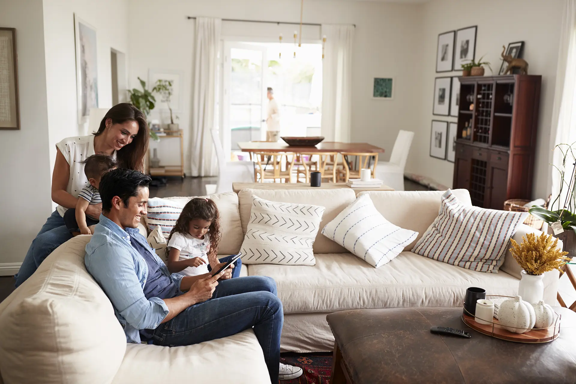 A couple and their two young kids sitting on a couch reviewing a tablet